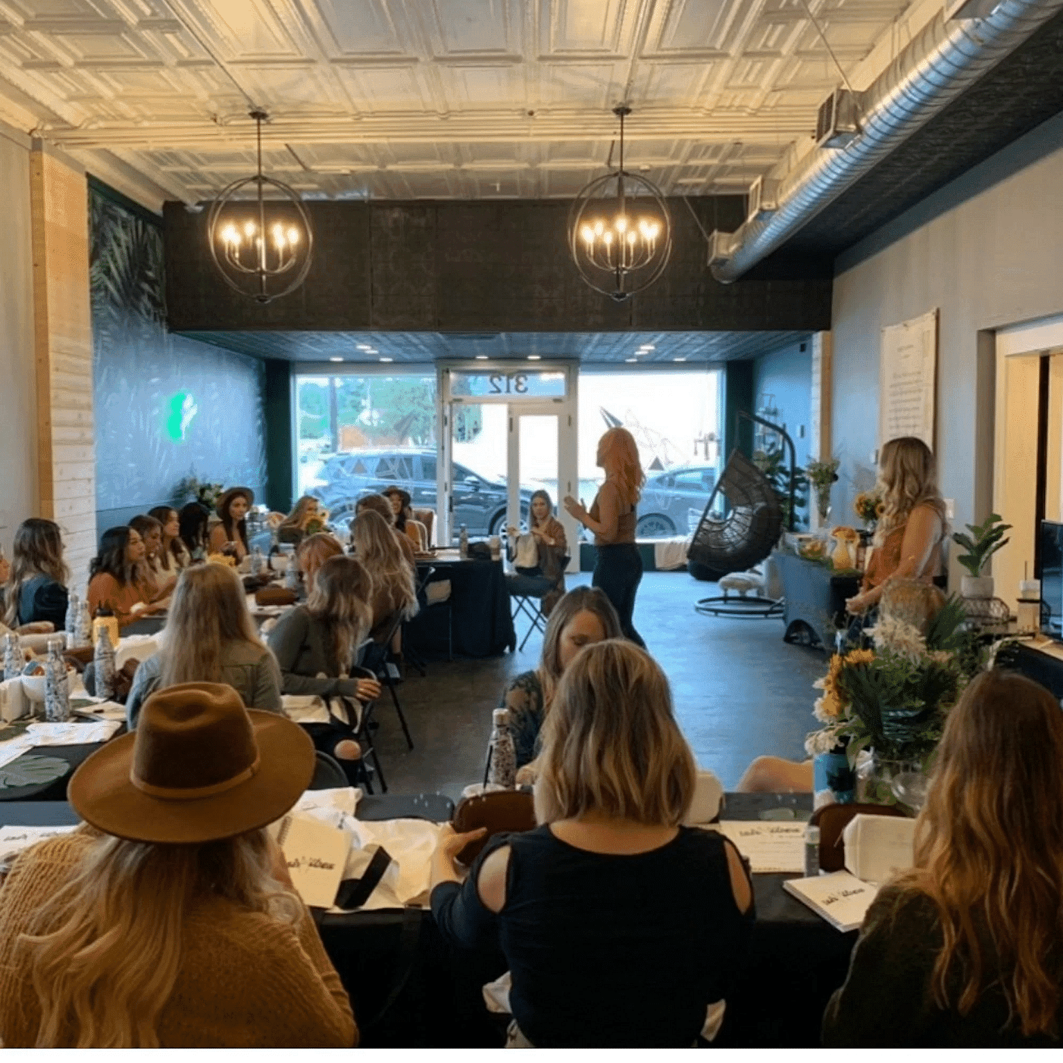 Workshop attendees sitting at tables in a chic, modern venue, engaging with a speaker at the front.