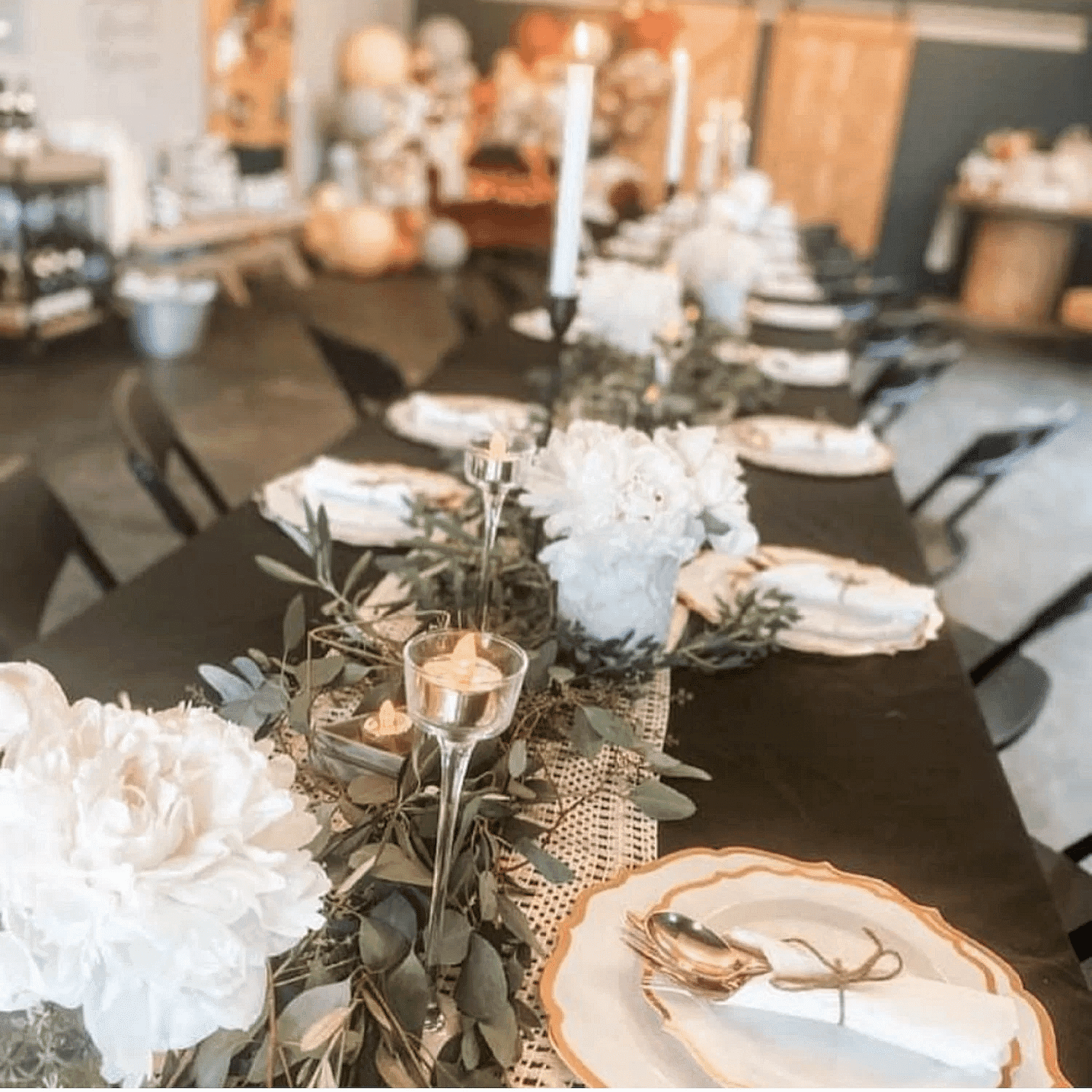 Elegant table setting with white flowers, candles, and greenery for a formal event or celebration.